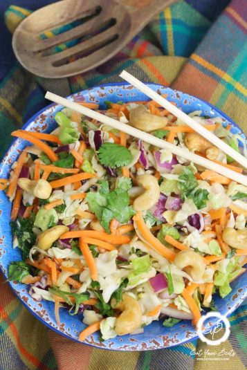 Fresh vegetable salad with carrots, cabbage, and cashews, served on a colorful plate.