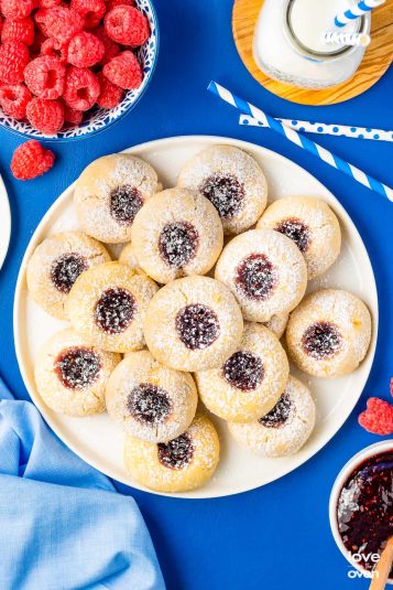 A plate of thumbprint cookies on a blue table.