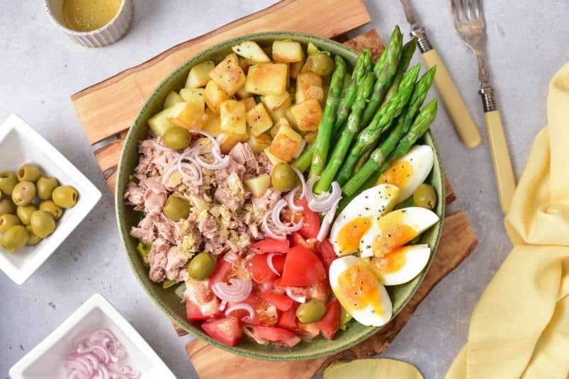 Fresh veggie salad bowl with boiled eggs, tuna, potatoes, asparagus, tomatoes, onions, and olives. Perfect healthy meal or side dish.