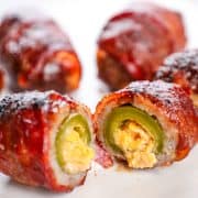 Crispy bacon-wrapped jalapeño poppers with creamy cheese filling on a white plate.