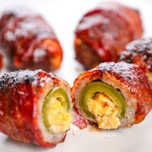 Crispy bacon-wrapped jalapeño poppers with creamy cheese filling on a white plate.