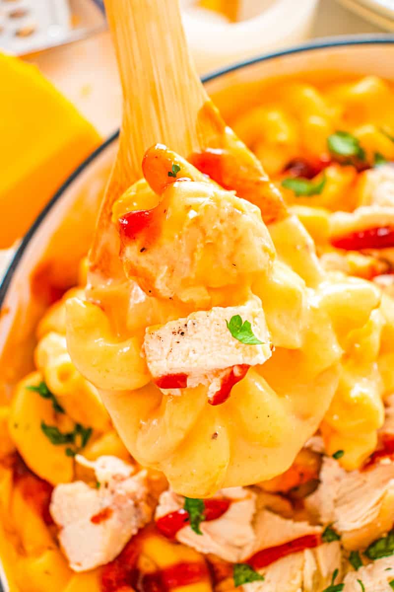 a wooden spoon with mac and cheese with chicken and BBQ sauce.