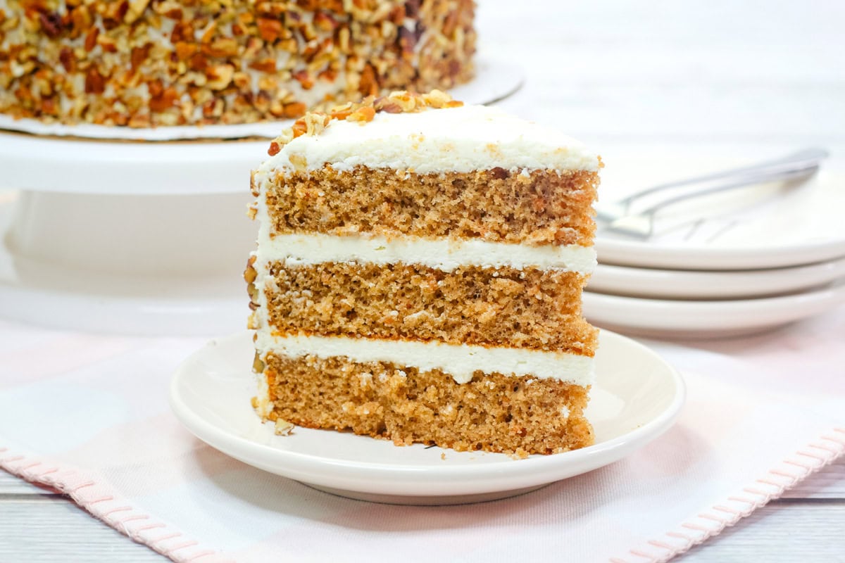 a slice of carrot cake with cream cheese icing and toasted pecans. 