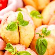 Fluffy peach cobbler muffins garnished with fresh basil on baking cloth.