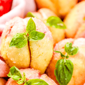 Fluffy peach cobbler muffins garnished with fresh basil on baking cloth.