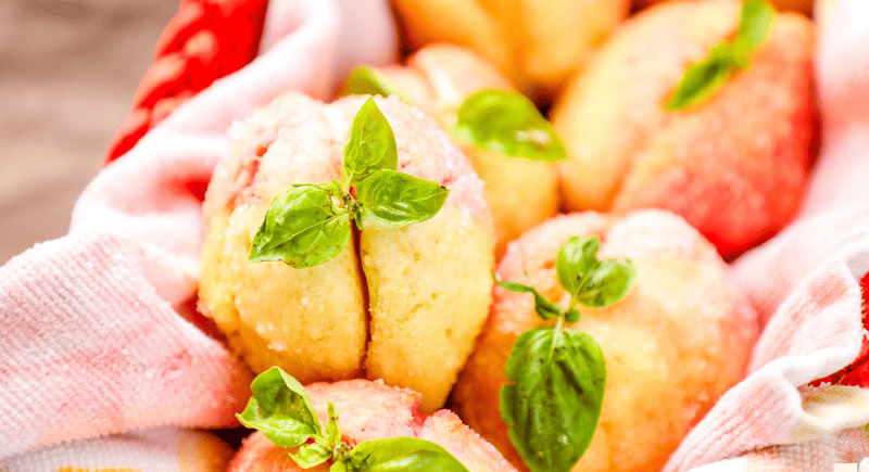 Fluffy peach cobbler muffins garnished with fresh basil on baking cloth.