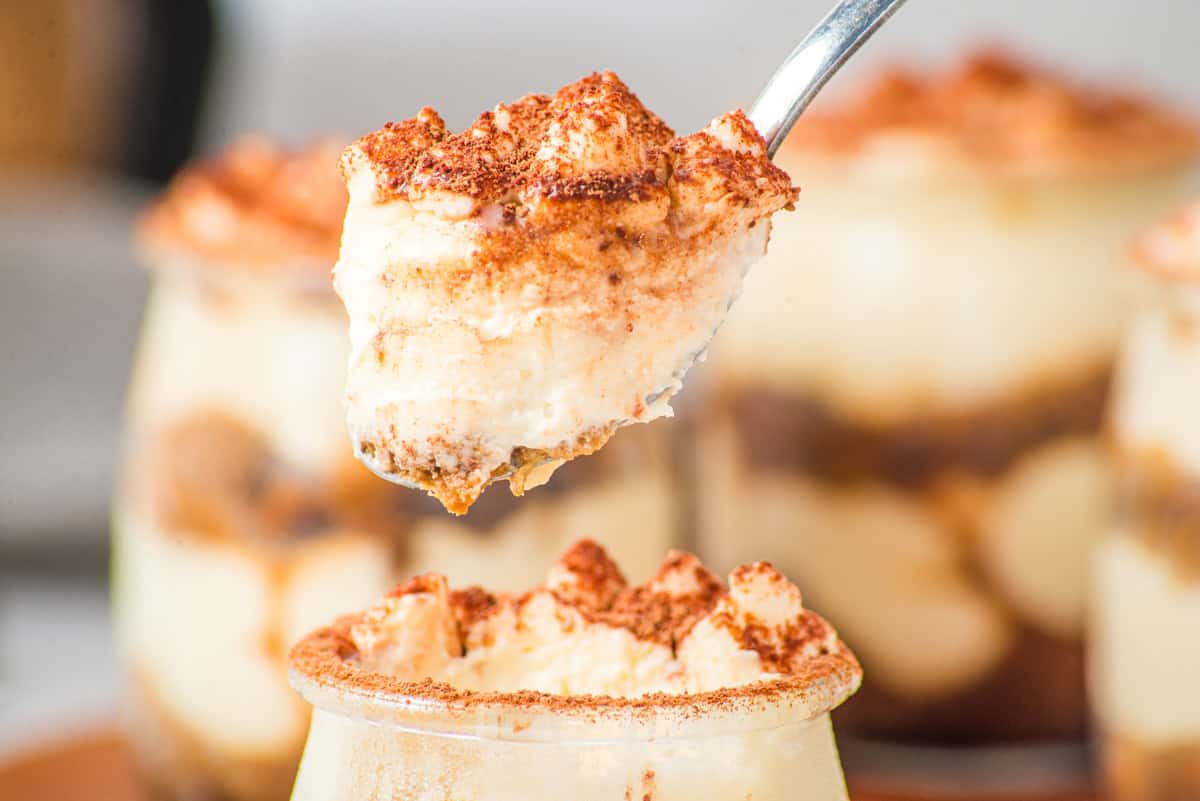a closeup of a spoonful of no bake tiramisu from a dessert cup. 