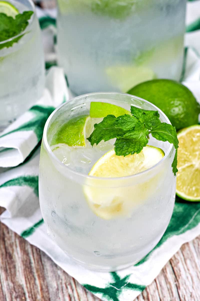 a Caipirinha cocktail garnished with lime slices and mint.