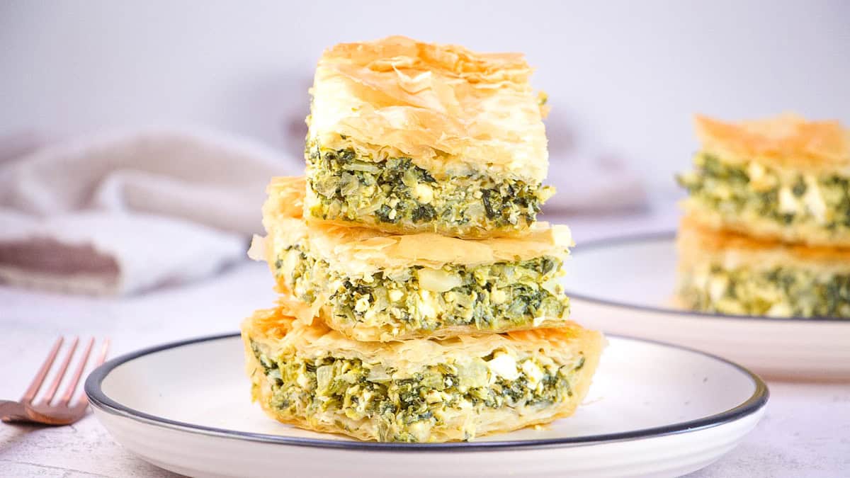 three slices of spanakopita with a spinach and feta cheese filling on a plate.