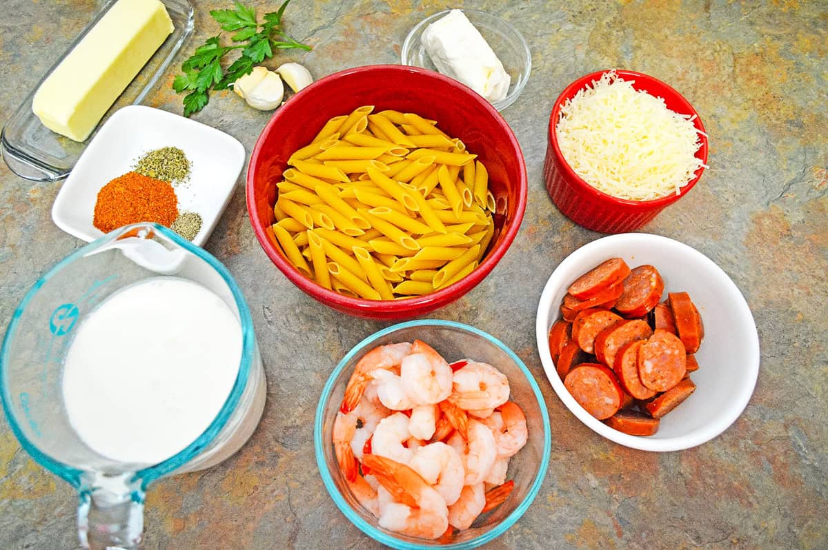 ingredients including penne pasta, heavy cream, butter, cream cheese, cajun seasoning, shrimp and and sausage. 