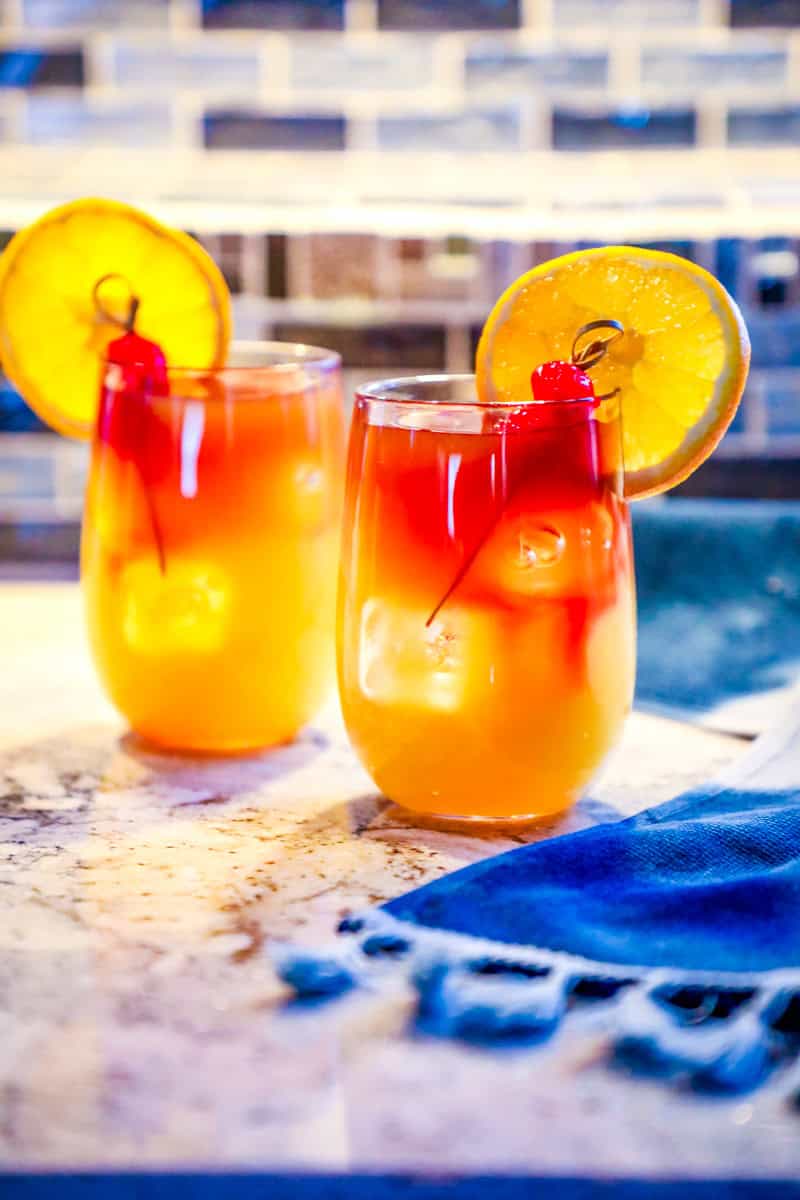 2 Mai Tai cocktails on a counter garnished with an orange and cherry.