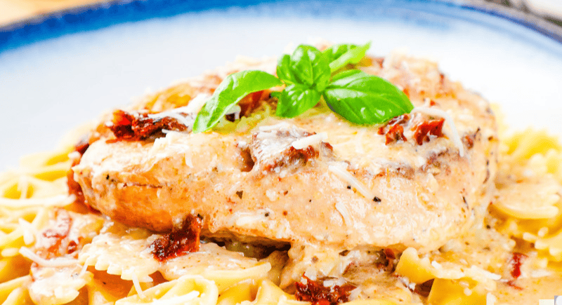 a square image of slow cooker marry me chicken with a sundried tomato cream sauce, cheese, and basil.