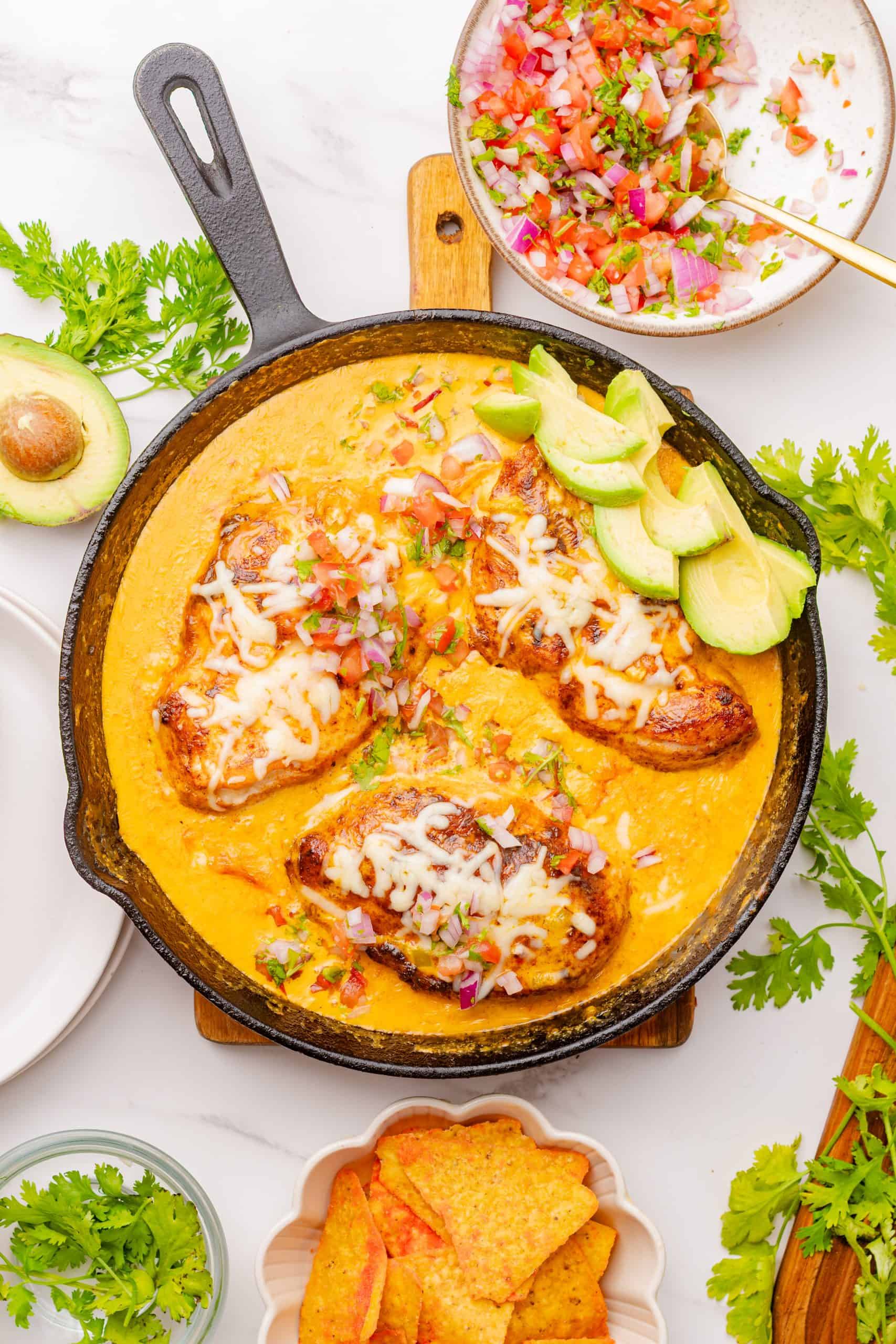 smother queso chicken skillet topped with cheese, pico de gallo, avocado, and cilantro. 