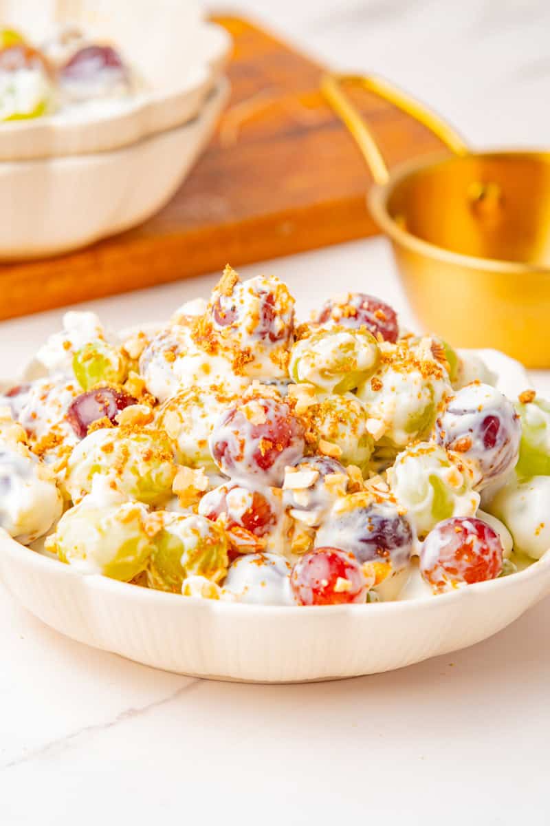 red and green grape salad in a creamy dressing topped with brown sugar and pecans.