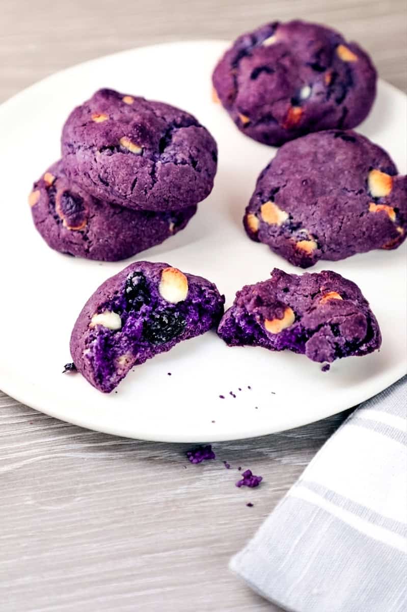 purple Blueberry cookies with white chocolate chips on a white plate.