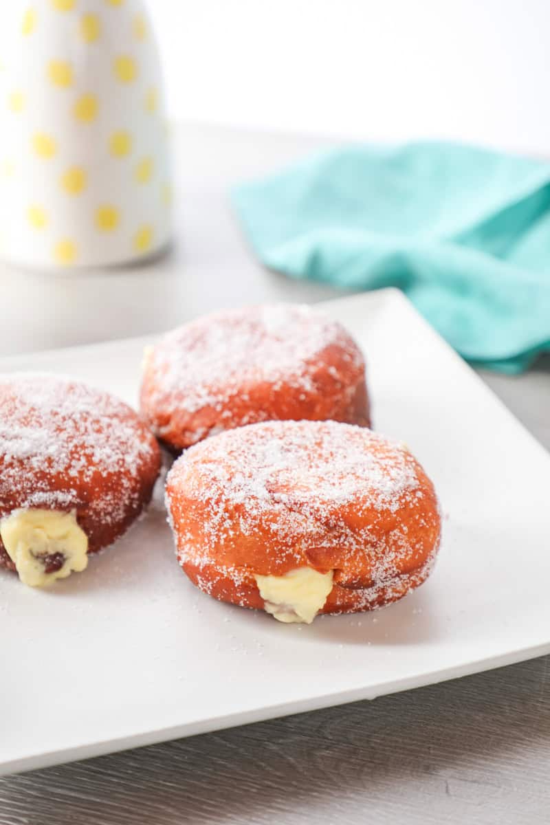 a Bomboloni doughnut dusted with powdered sugar and fill with pastry cream.