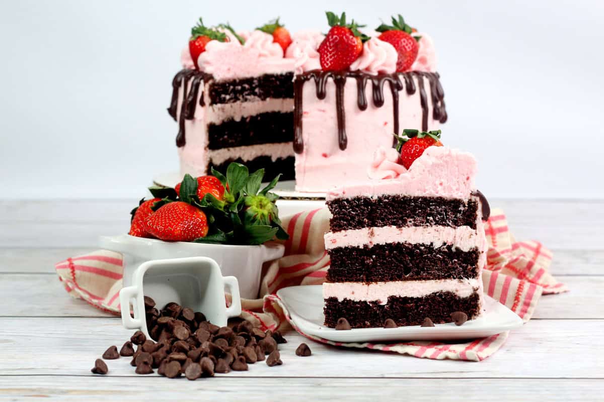 a slice of chocolate cake with fresh strawberry buttercream and a fresh strawberry on top.