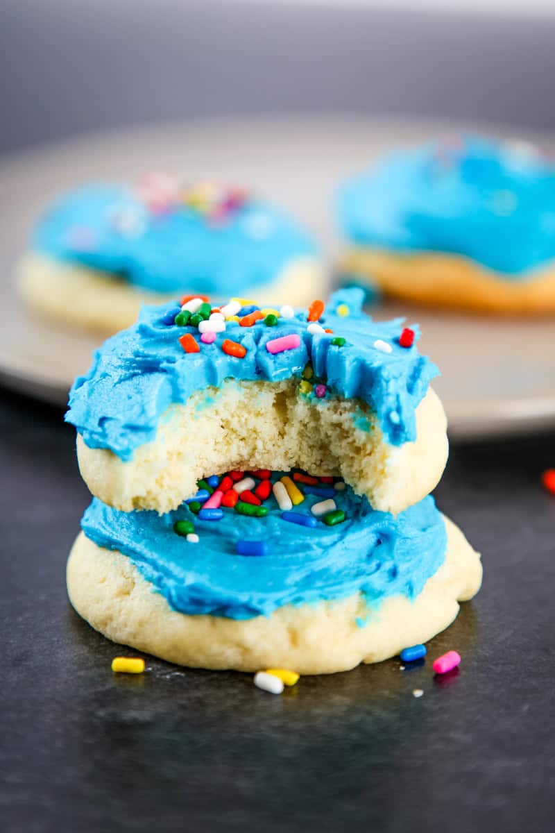 a homemade Lofthouse cookie topped with blue frosting and sprinkles with a bite taken out of it.
