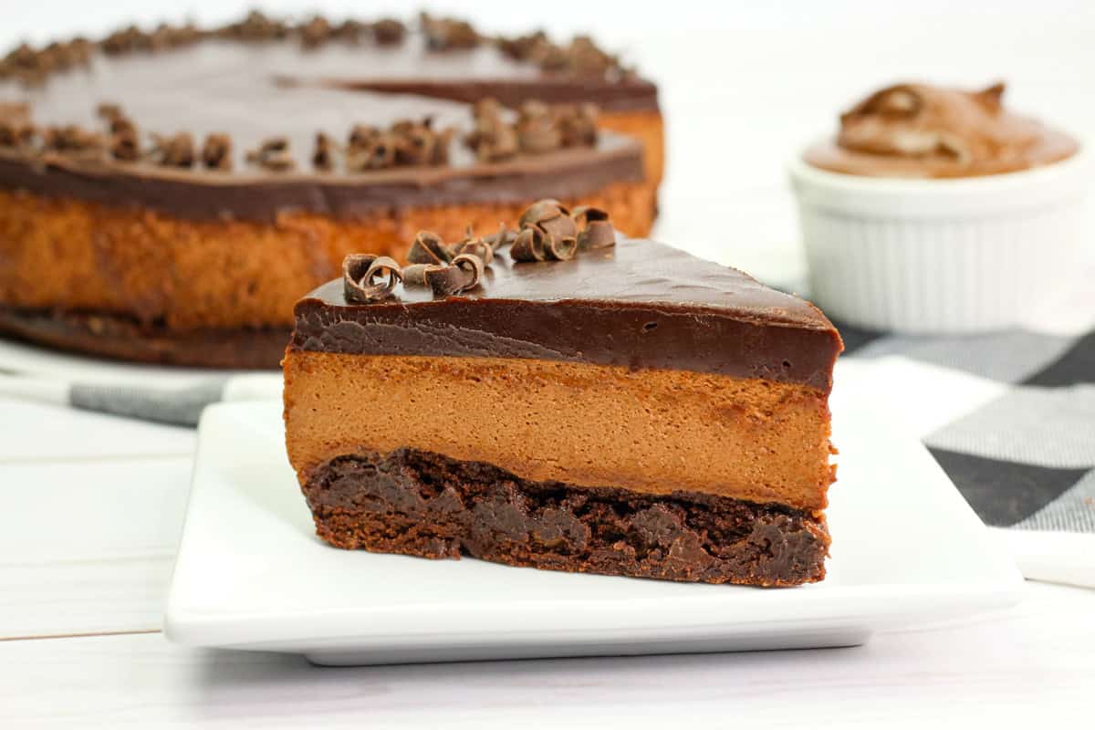 a closeup of a three layer Nutella mousse cake with Nutella ganache with the full cake in the background.