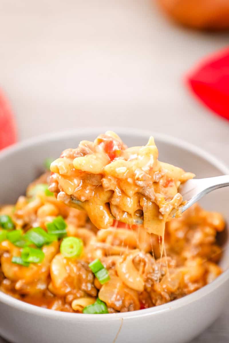 a bowl of taco pasta with ground beef, cheese, tomatoes, and green onions.