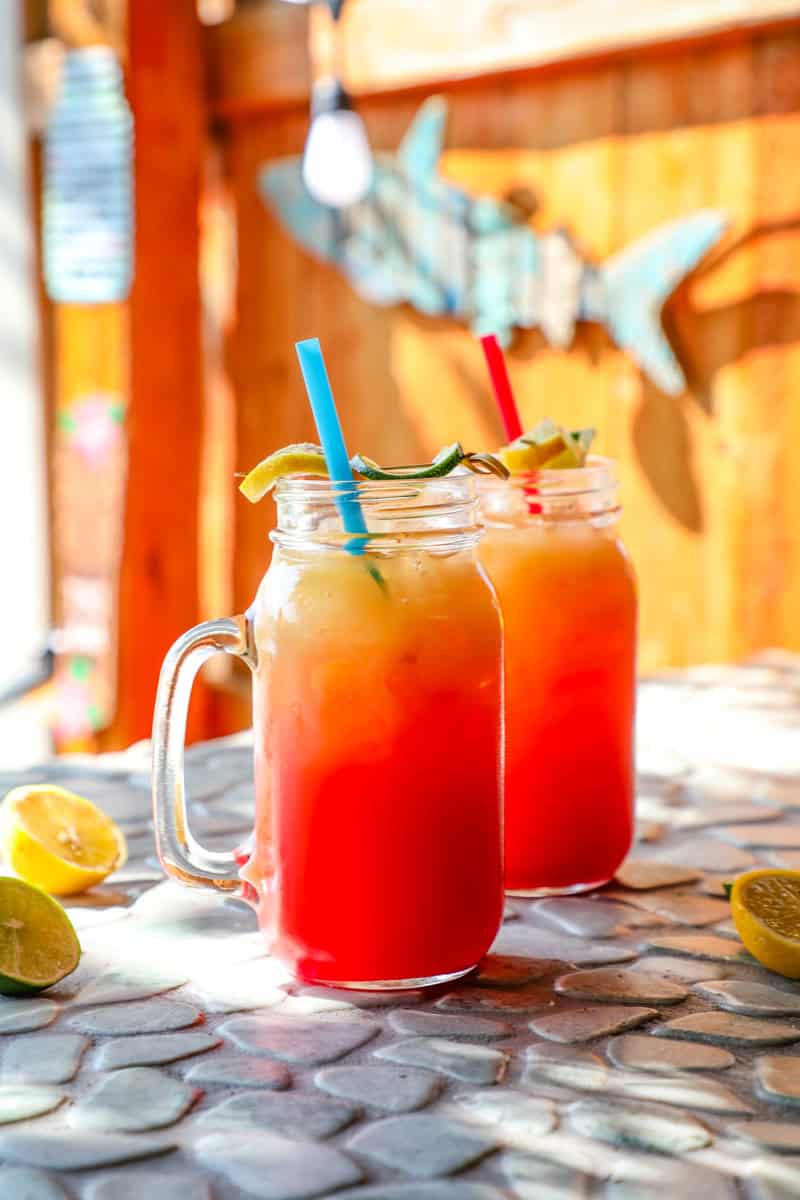 two glasses of rum punch on a stone counter top.
