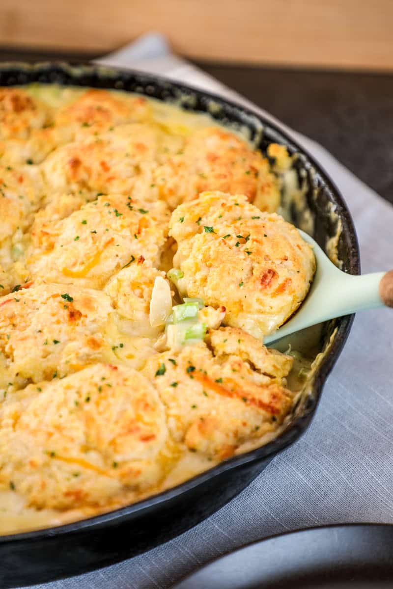 a spoon lifting out a serving of cheddar bay biscuit pot pie with chicken and vegetables.