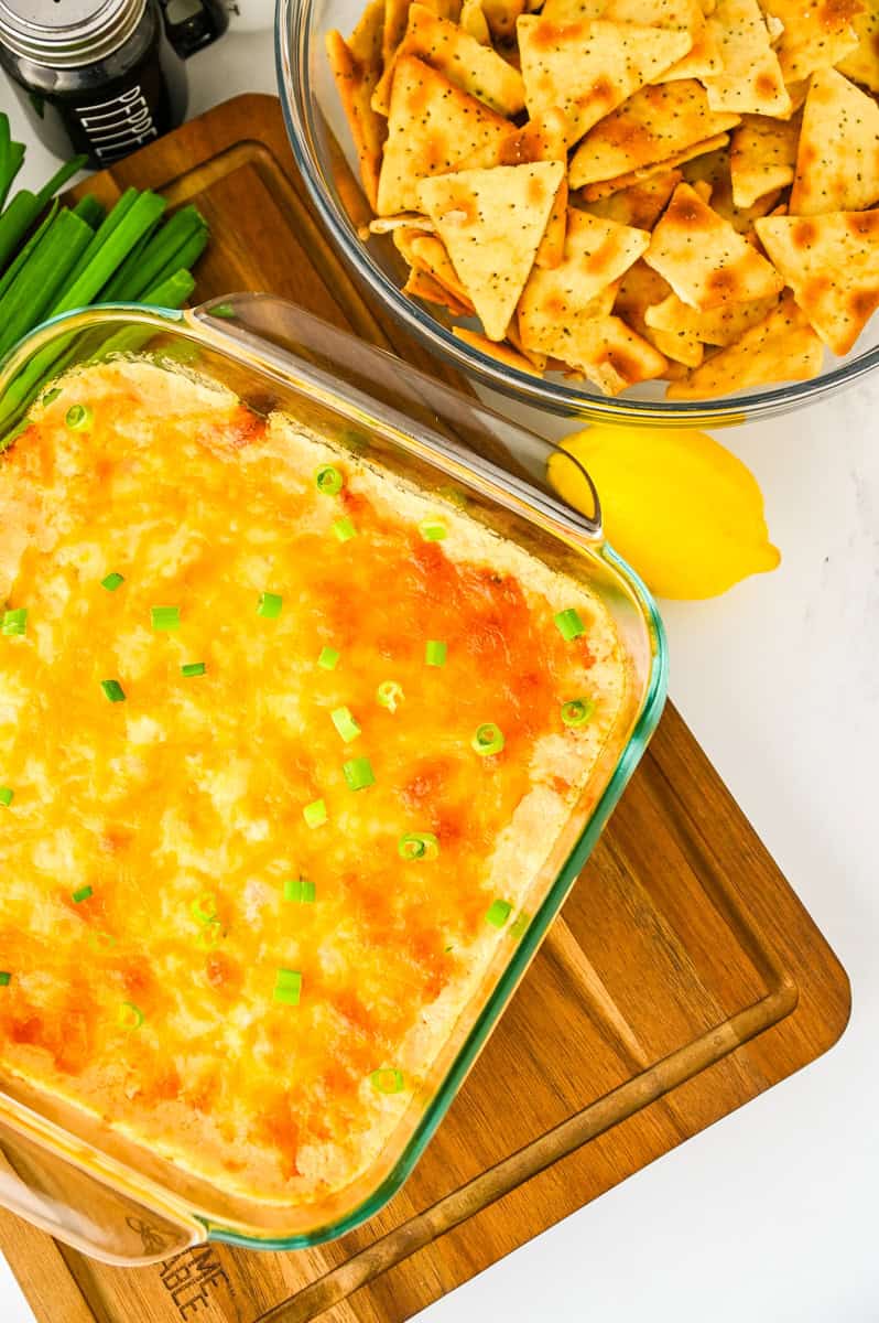 a glass pan of creamy shrimp and crab dip on a cutting board.