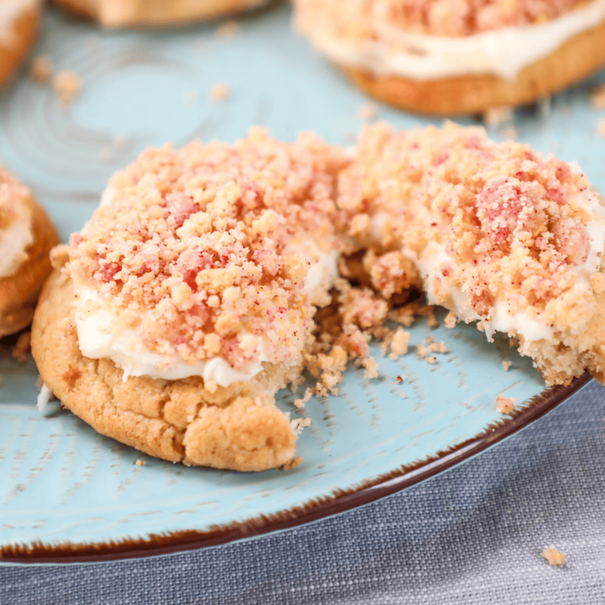 a vanilla cookie with frosting and a strawberry crumble cut in half. 