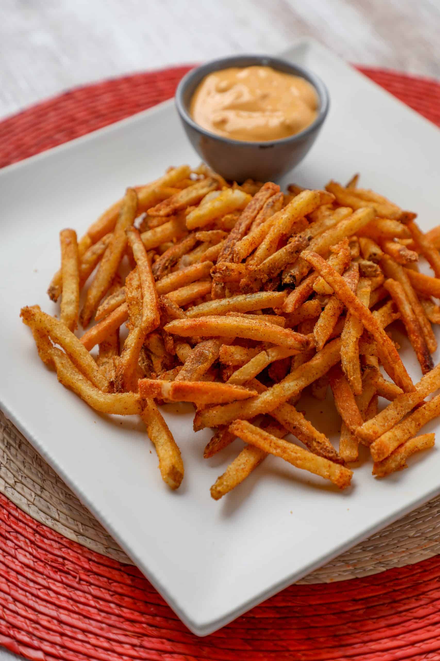 homemade nacho fries with cheese sauce in the background.