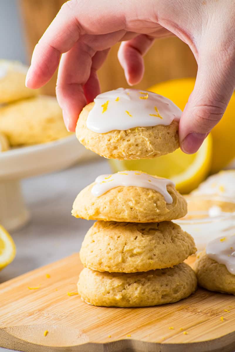 a hand picking up a soft lemon cookie with lemon glaze. 