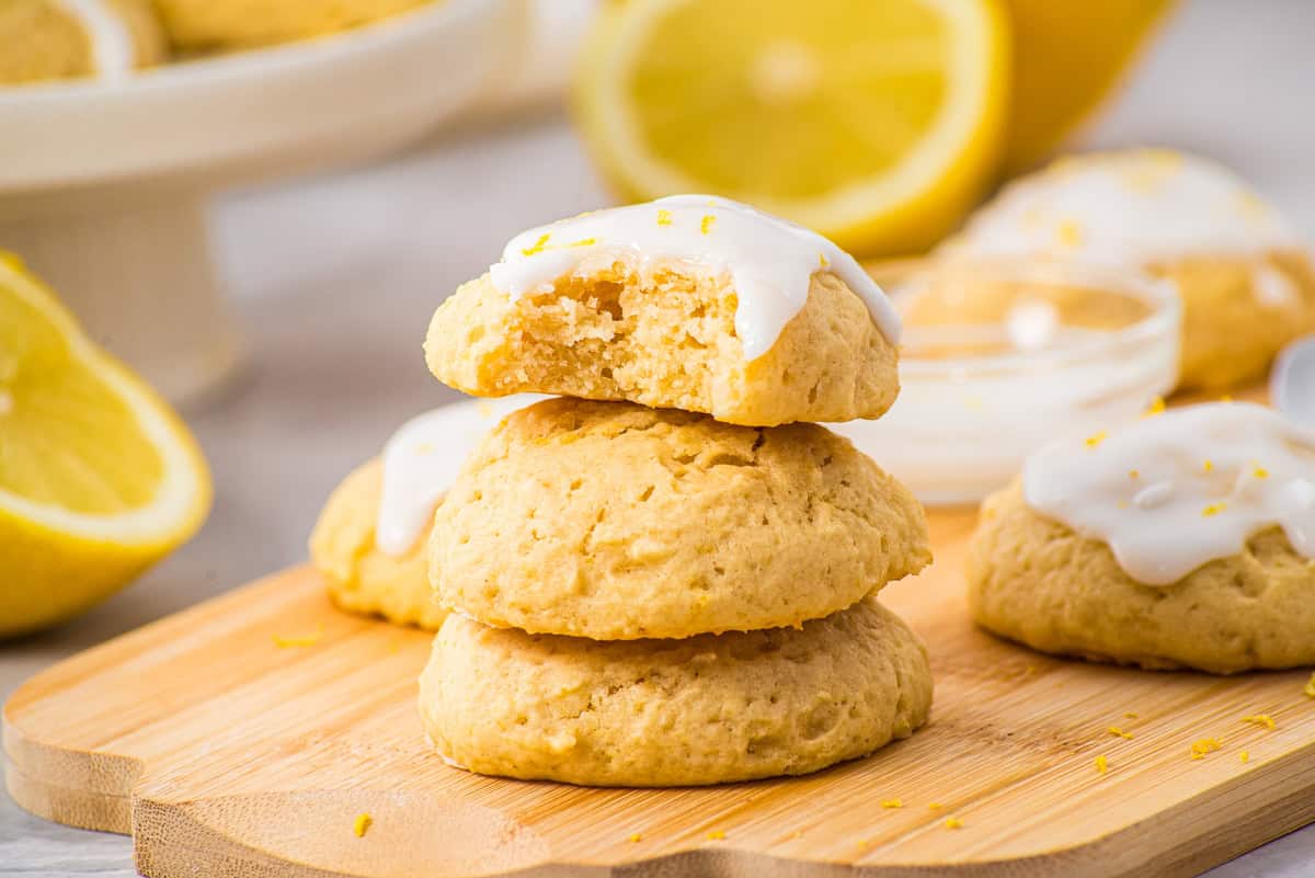 three lemon cookies stacked on top of each other and topped with glaze and lemon zest.