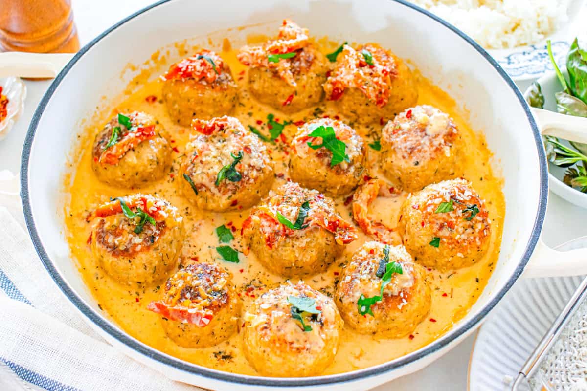 a skillet of chicken and sundried tomato meatballs in a cream sauce.