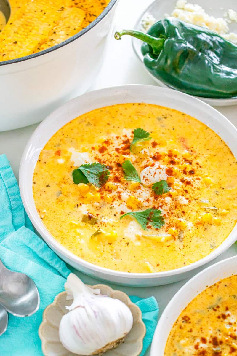 a bowl of Mexican street corn chowder topped with Mexican crema, cilantro, and chili powder.