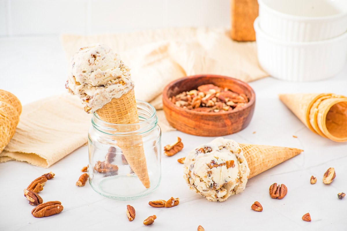 two ice cream cones filled with no churn butter pecan ice cream one in a jar and one lying down.