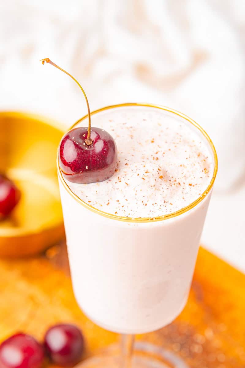 a closeup of a brandy alexander with ice cream garnished with a cherry and nutmeg. 