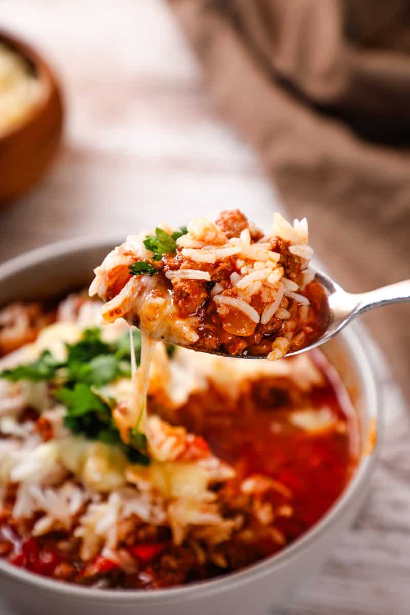 a spoonful of slow cooker stuffed pepper soup with rice, shredded cheese, ground beef, and sausage.