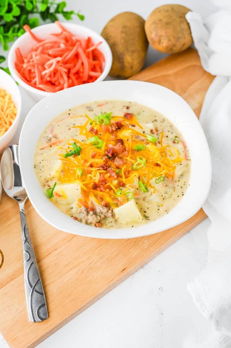 a bowl of bacon cheeseburger potato soup topped with cheese and more bacon.