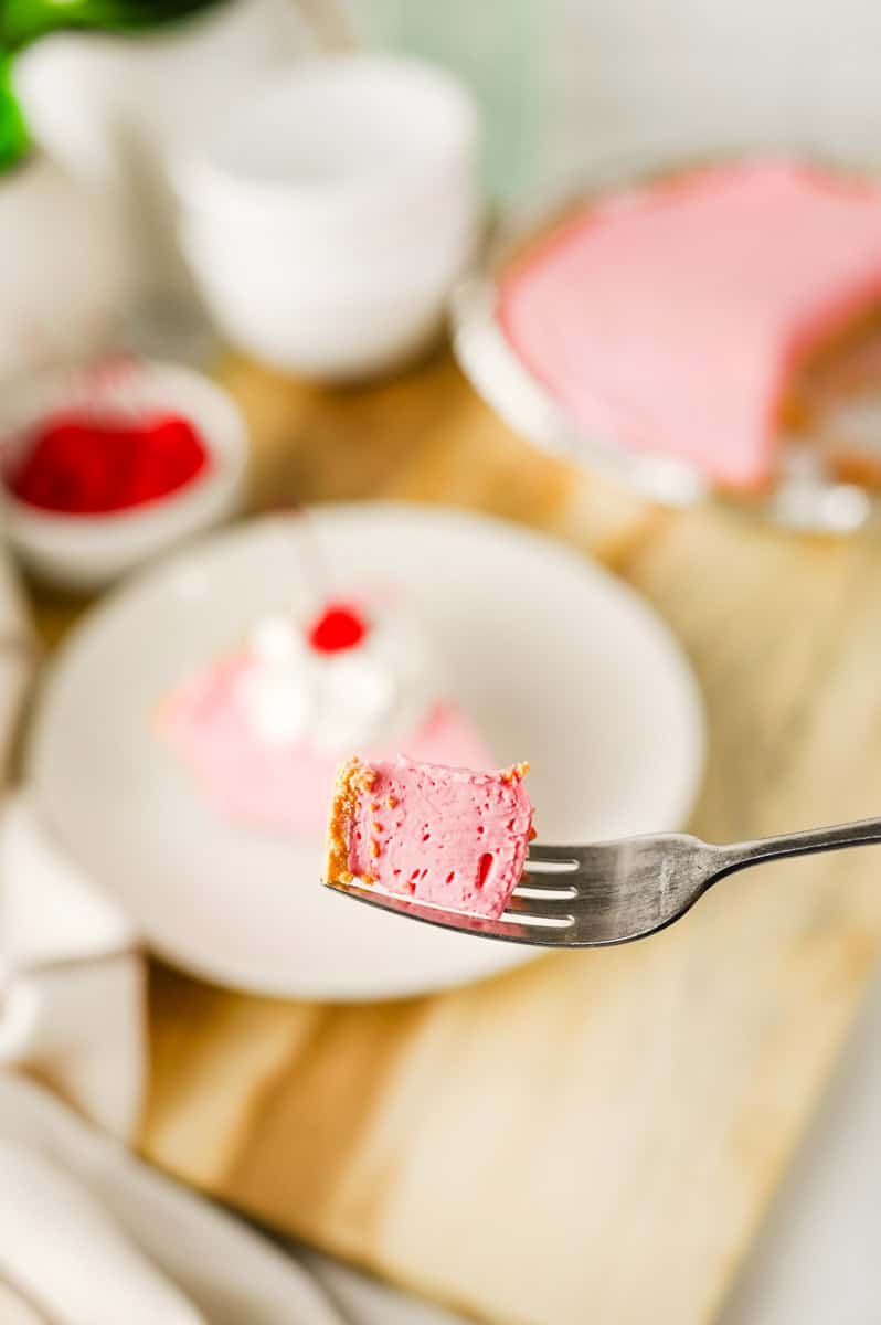 a fork with a bite of cherry Kool Aid pie with a graham cracker crust.