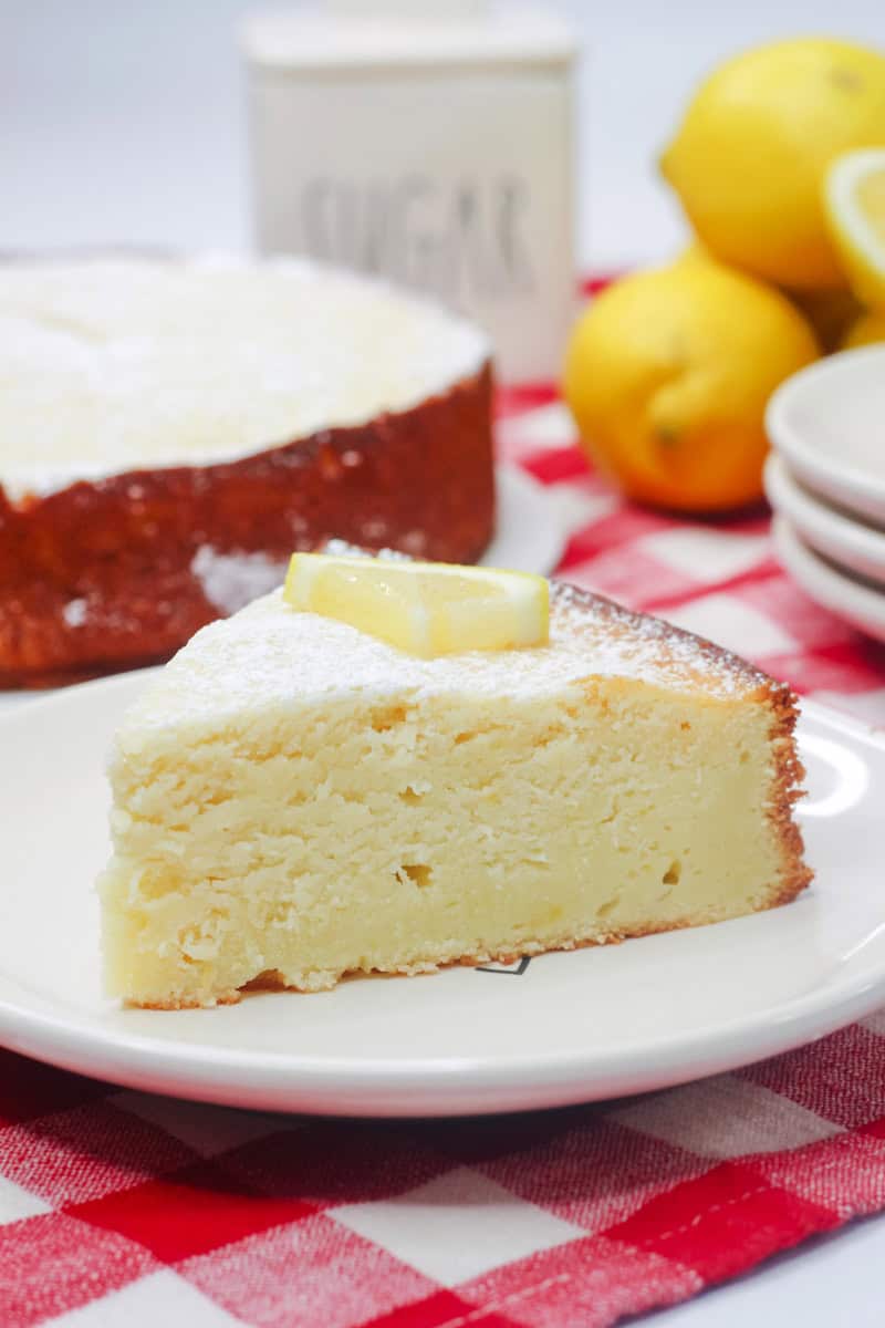 a slice of lemon ricotta cake topped with powdered sugar and a slice of lemon.