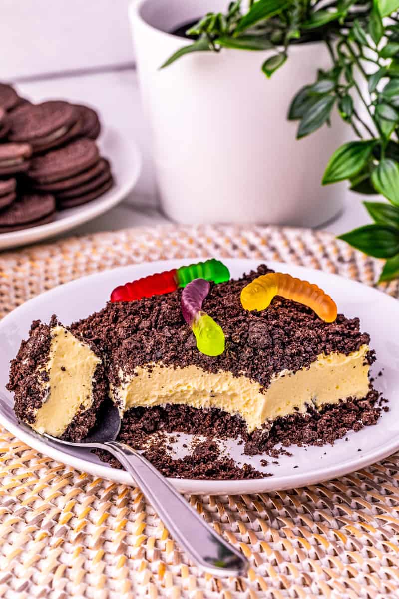 a slice of dirt cake topped with oreo cookie crumbs and gummy worms.