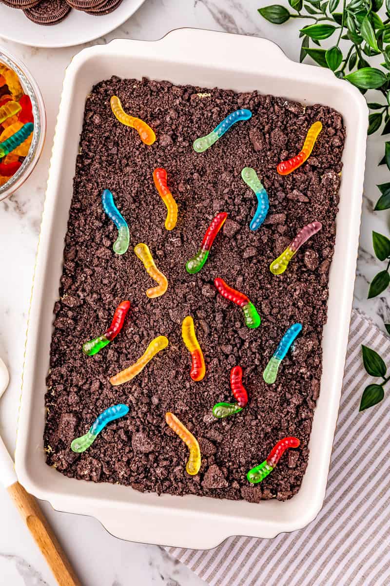 a 9x13 pan of dirt cake with oreo cookies and multicolored gummy worms.
