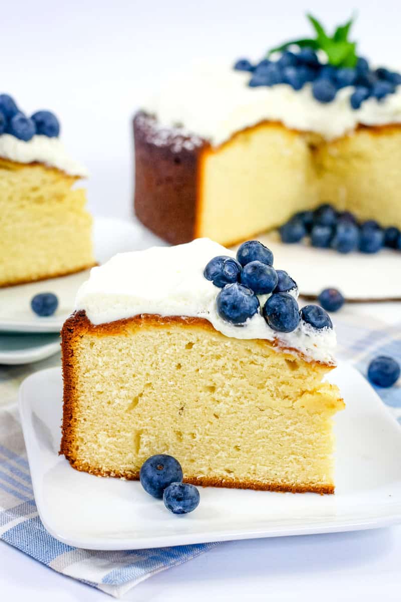 a slice of sweetened condensed milk cake topped with whipped cream and blueberries.