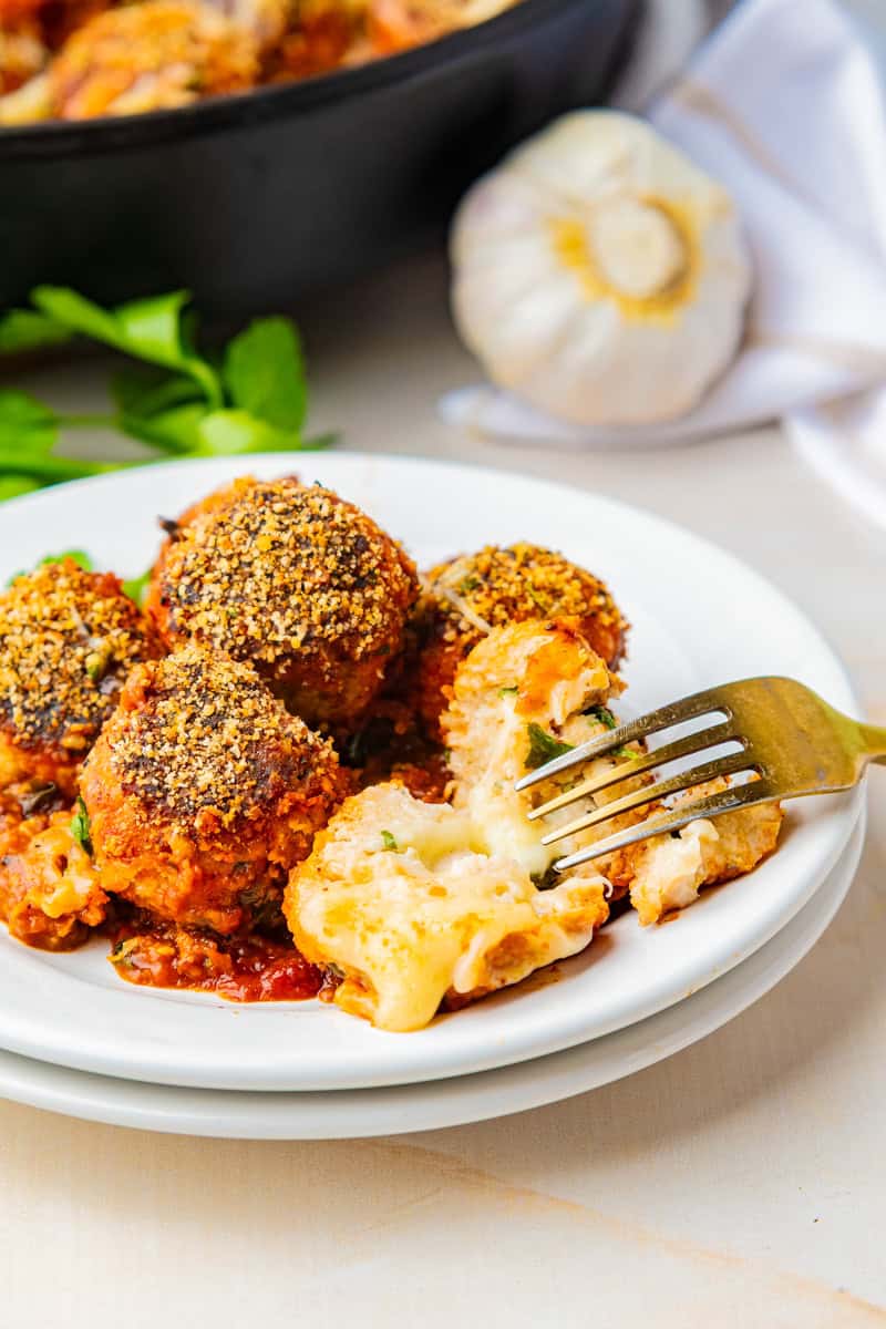 a fork cutting into a mozzarella stuffed chicken meatball.