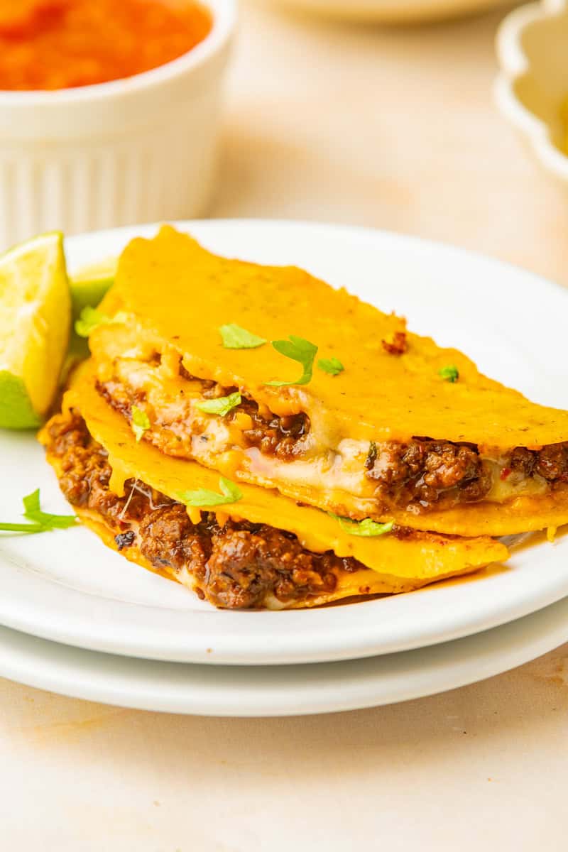 a plate of two crispy beef tacos with cheese.