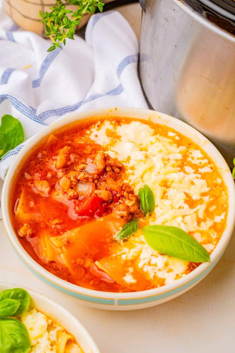 a bowl of lasagna soup with beef, sausage, noodles, and a ricotta, parmesan and mozzarella topping.
